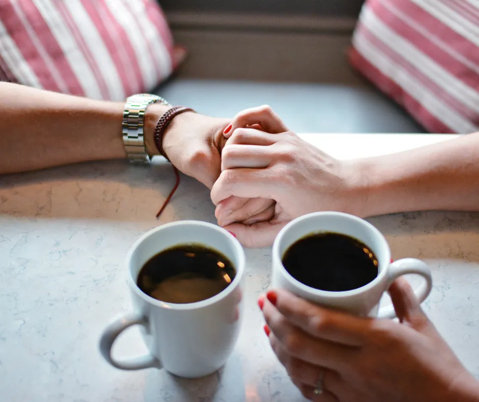 Couple holding hands over coffee cups on a table