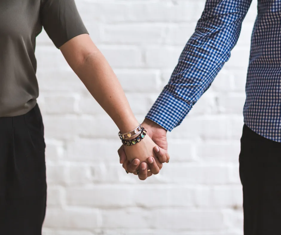 Couple holding hands, showing affection and connection.