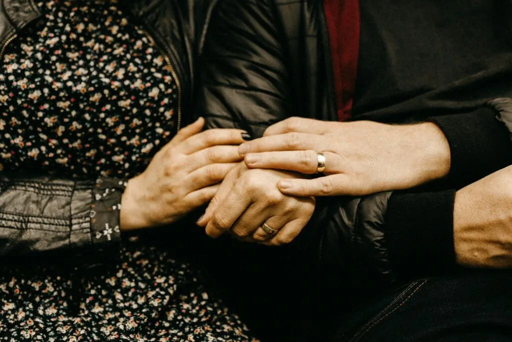 Couple holding hands, showing wedding rings. Applying for a partner visa? We can help.