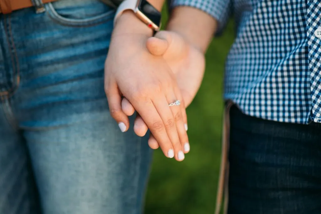 Couple holding hands, showcasing a diamond engagement ring. Prospective marriage visa.