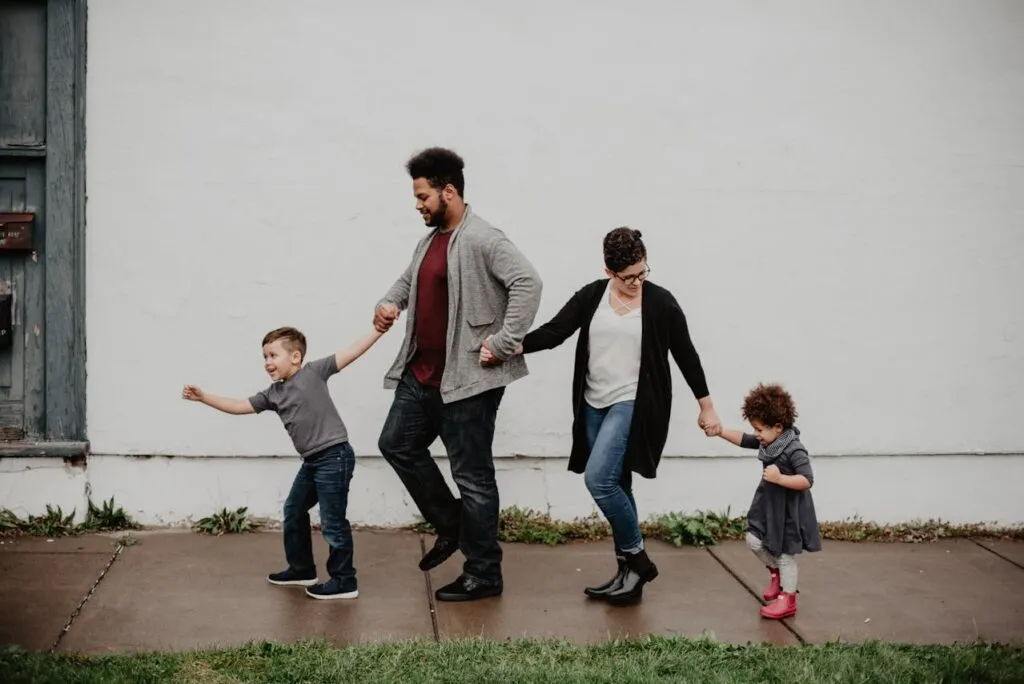Happy family of four walking hand-in-hand. Parents and two children enjoying a stroll.