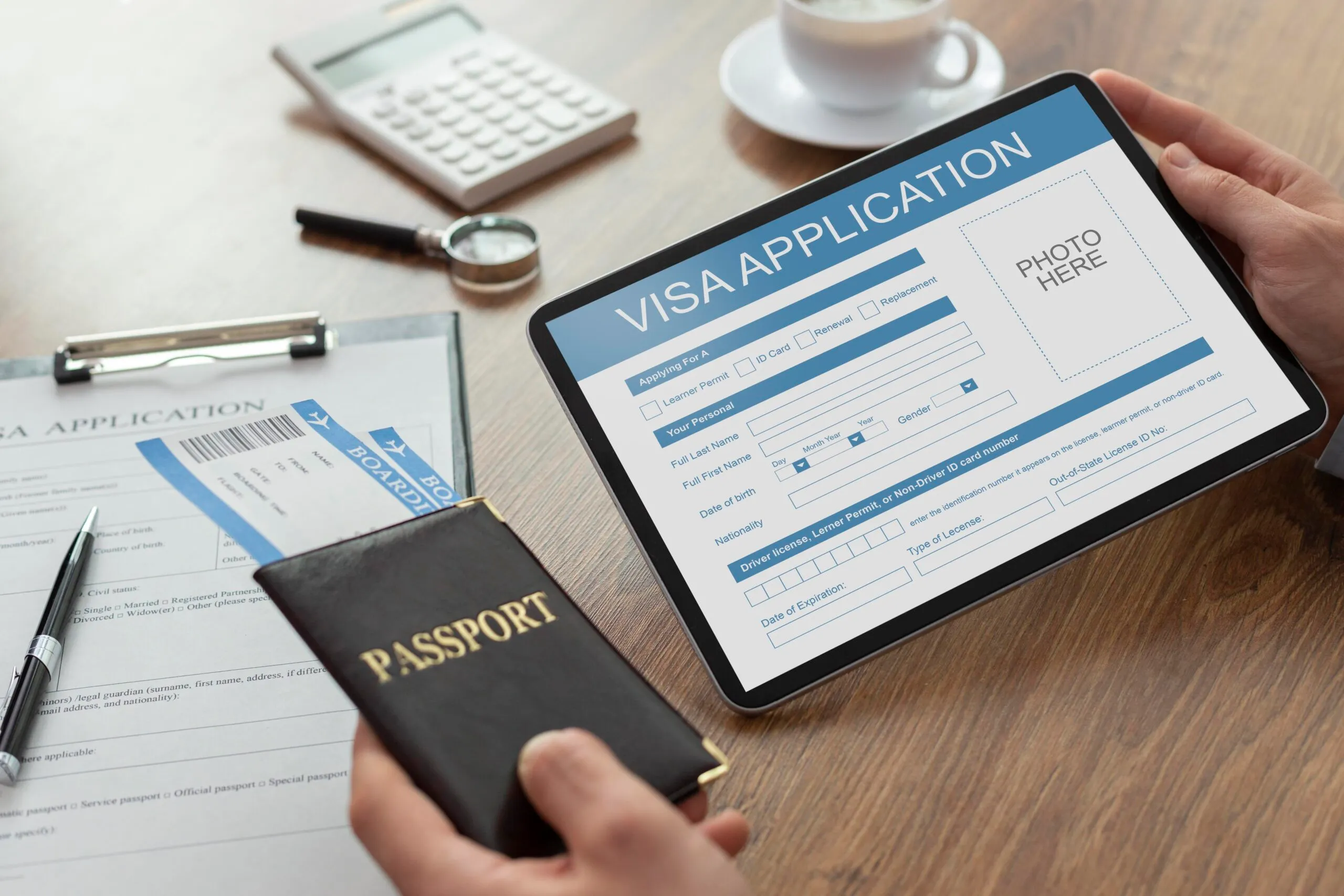 Person completing an online visa application on a tablet, holding a passport.