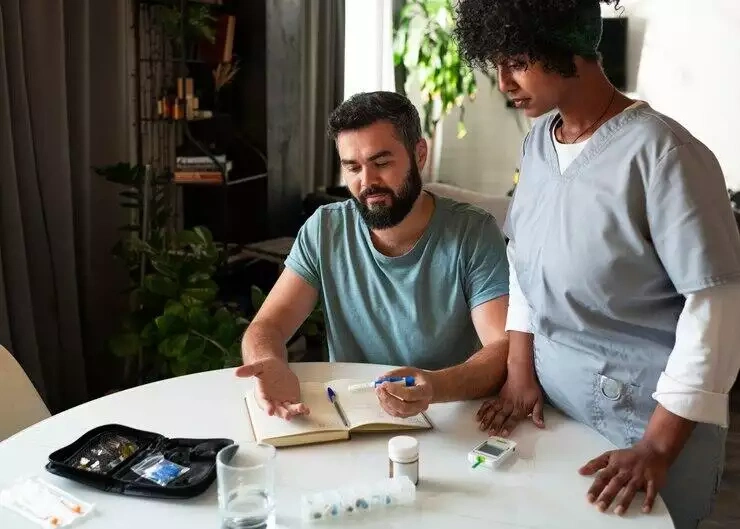 Nurse and patient reviewing medical records and supplies during a home healthcare visit.