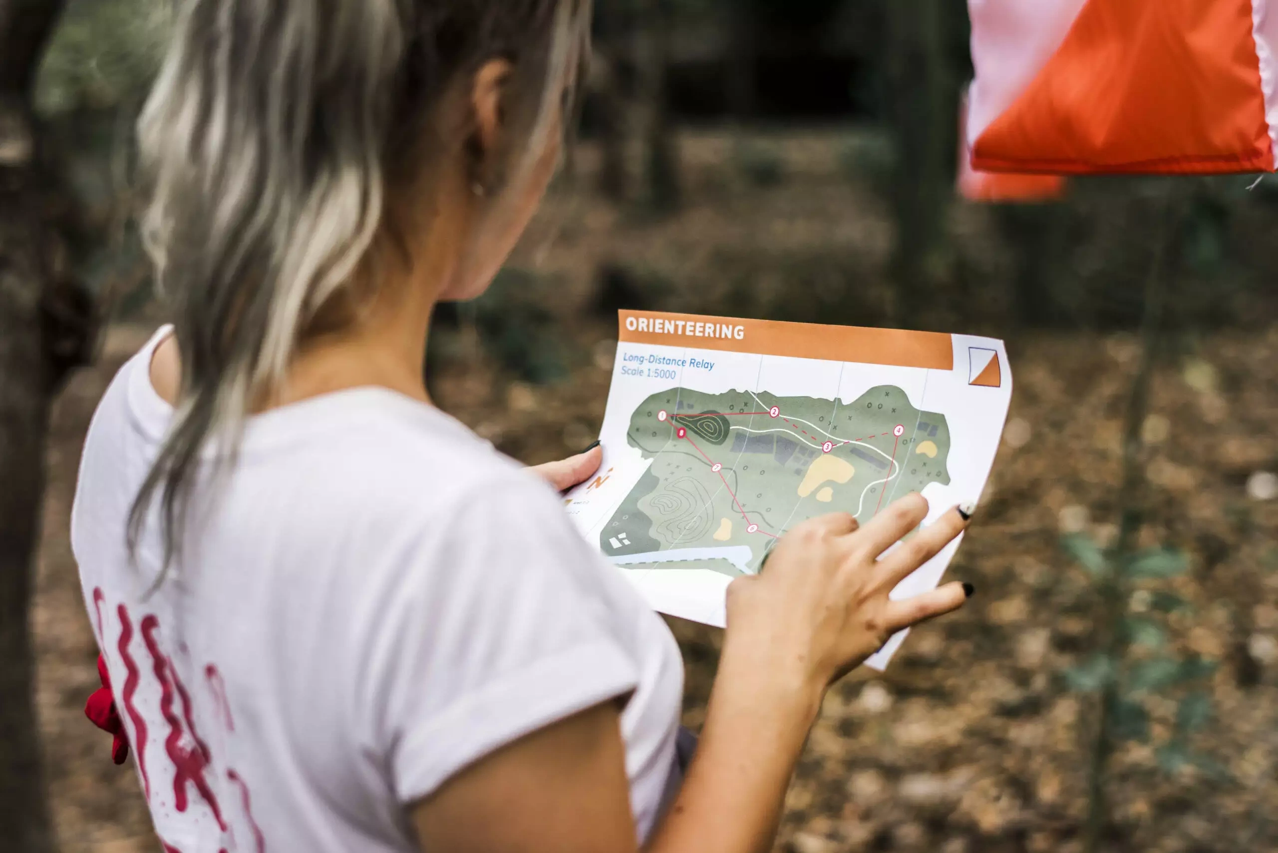 Woman reading orienteering map in a forest setting