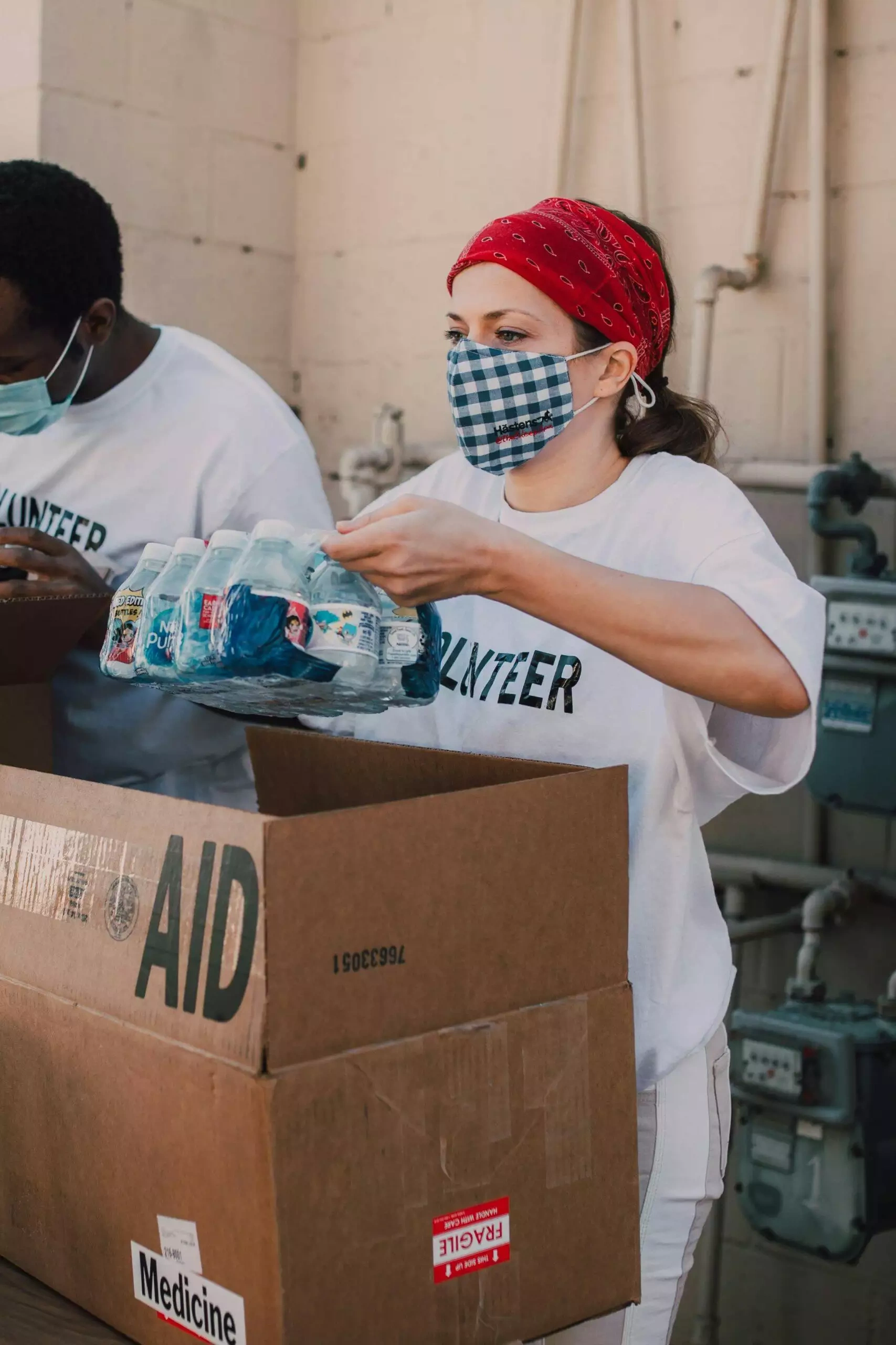 Volunteers wearing masks pack bottled water into an 