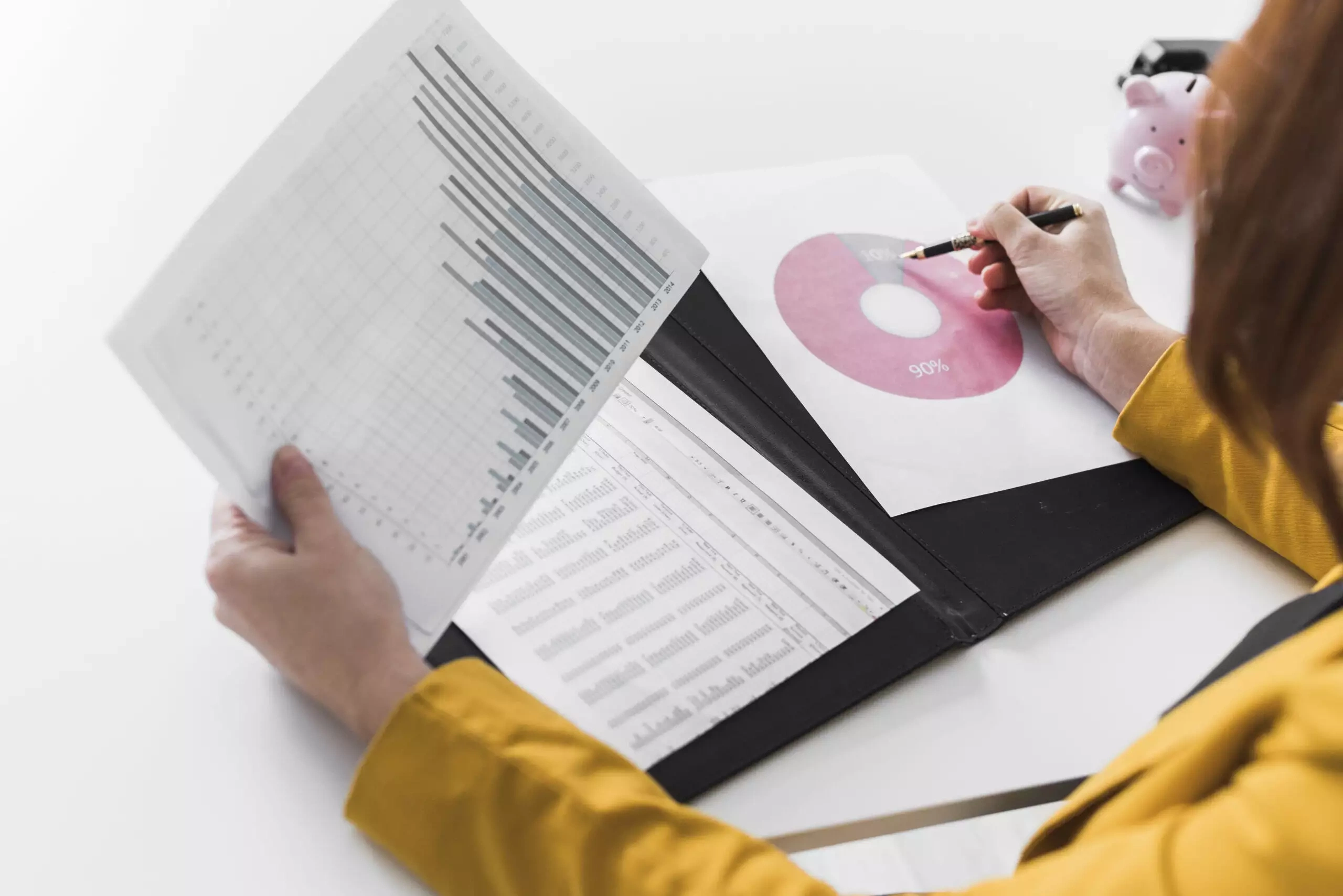 Woman analyzing financial graphs and pie chart on a desk