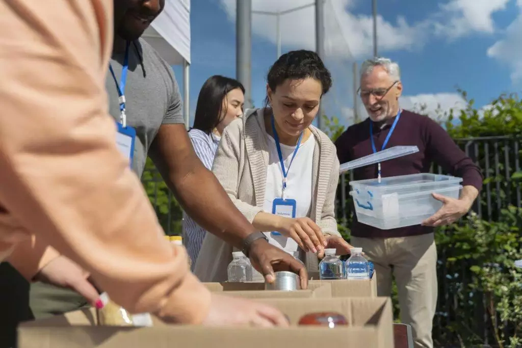 Volunteers sorting donations at a charity event. One volunteer's name tag reads 