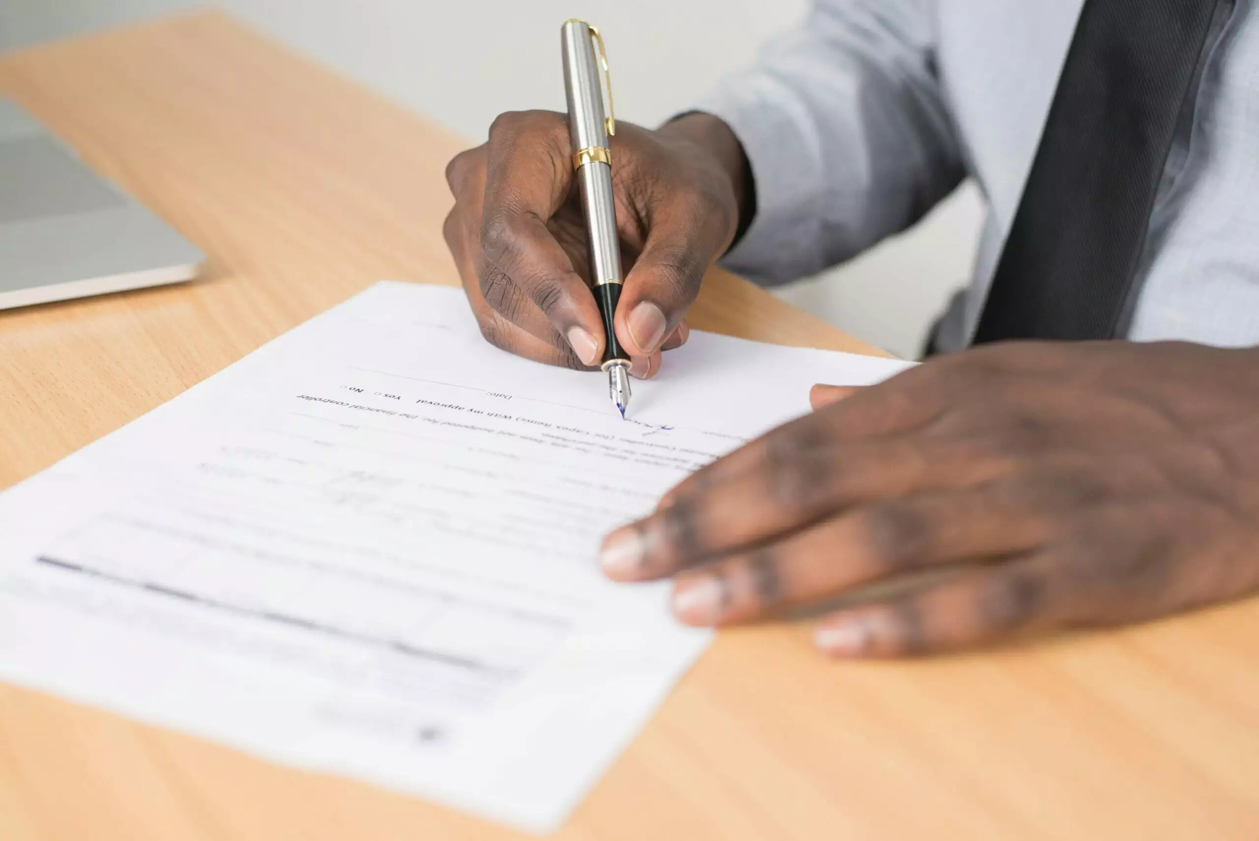 Person signing a document with a pen, creating a not-for-profit succession plan.