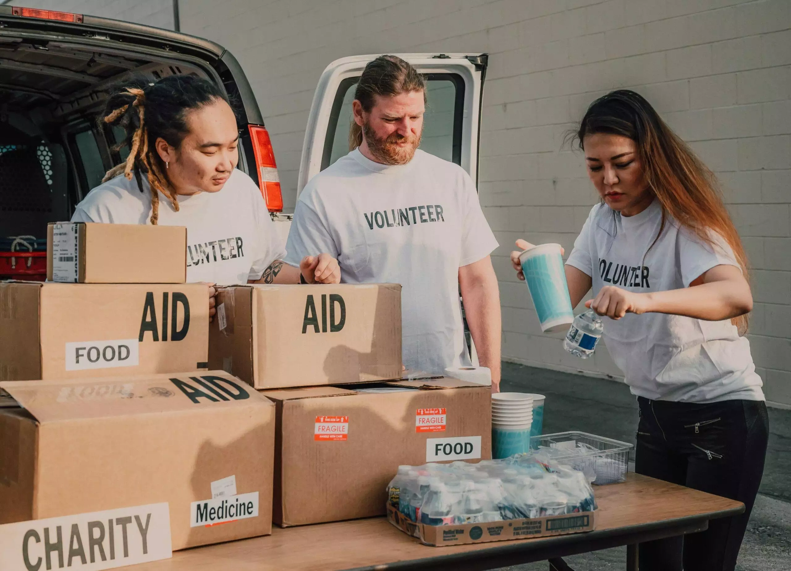 Volunteers sorting donations of food, medicine, and aid for charity. Volunteer training and screening are key to effective charity governance.