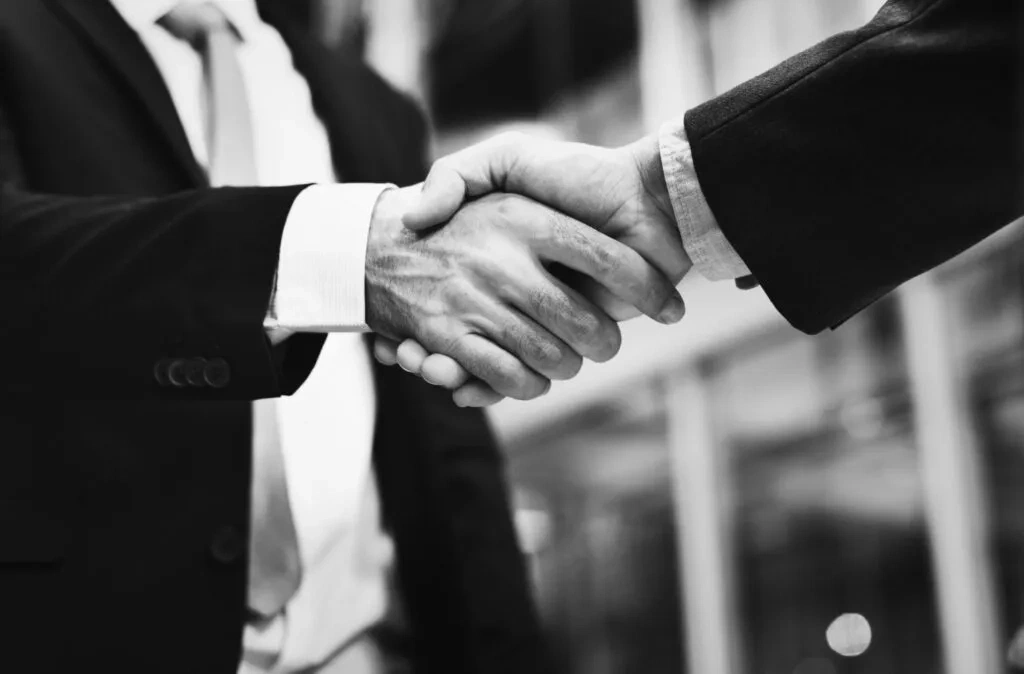 Two businessmen shaking hands, signifying a successful merger or collaboration. NFP lawyers.