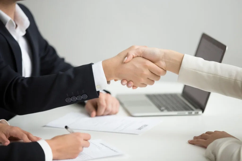 Businesspeople shaking hands, signifying a successful job interview or partnership. Employment lawyers for NFPs & charities.