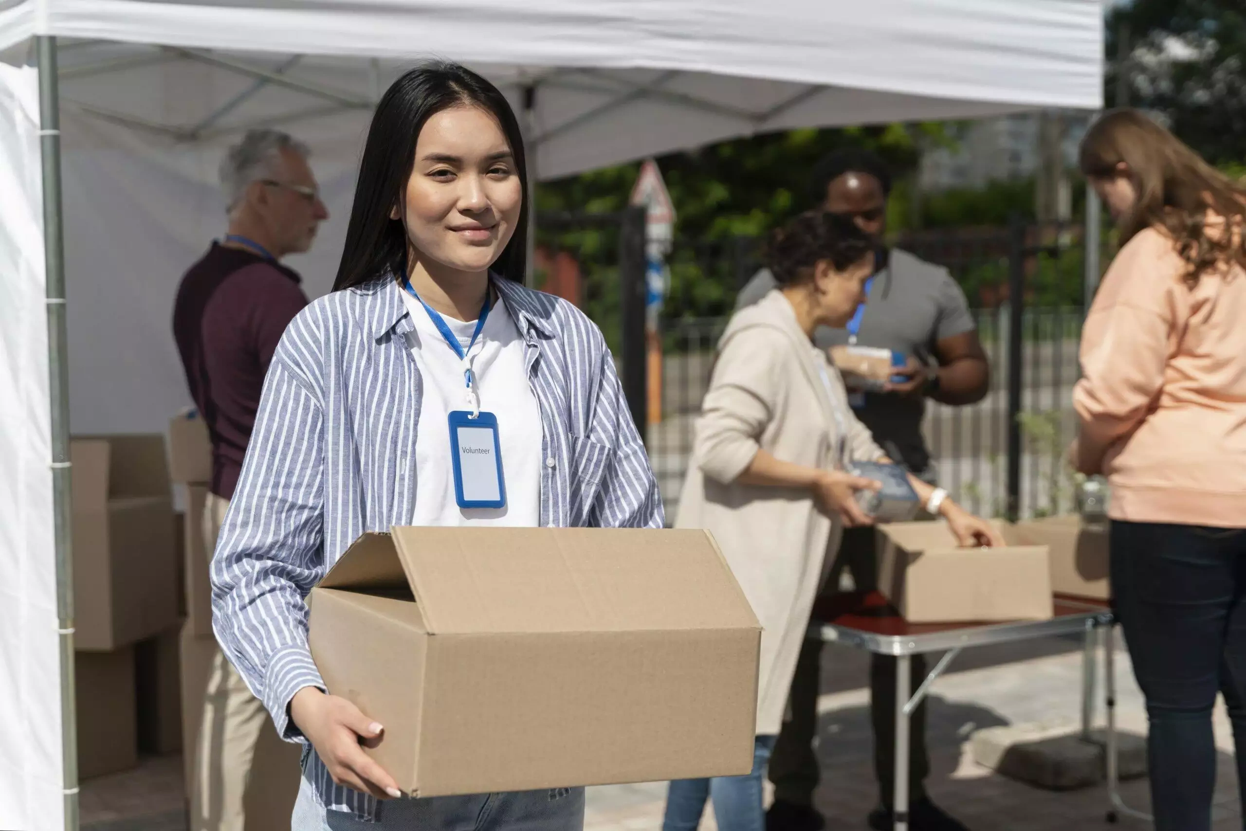 Smiling female volunteer holding a donation box at a charity event.