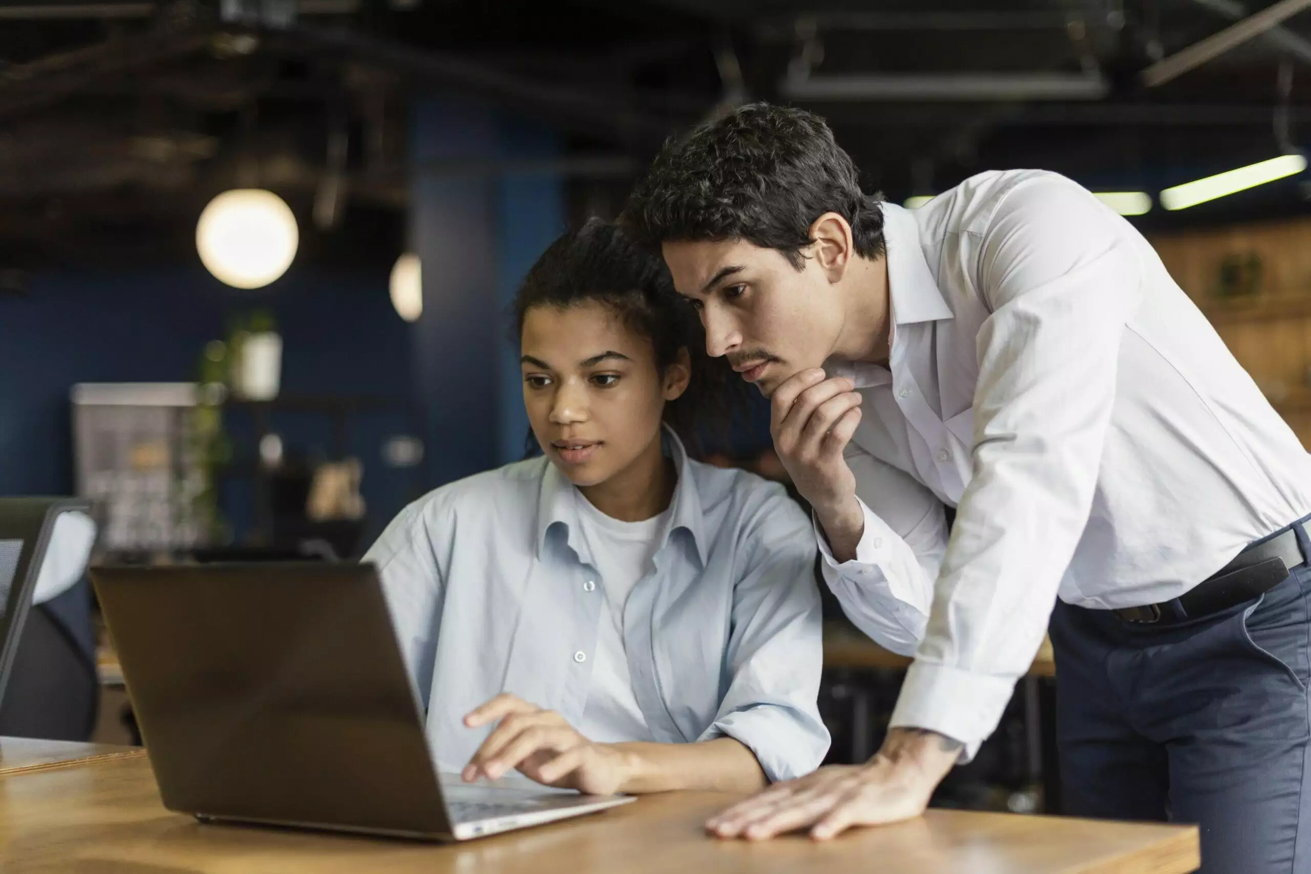 Two colleagues collaborate on a laptop, reviewing user-generated content.