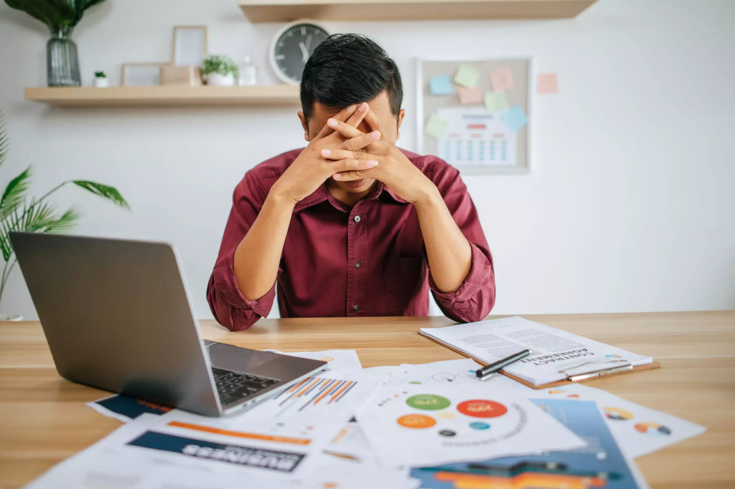 Stressed man at desk with laptop and financial documents