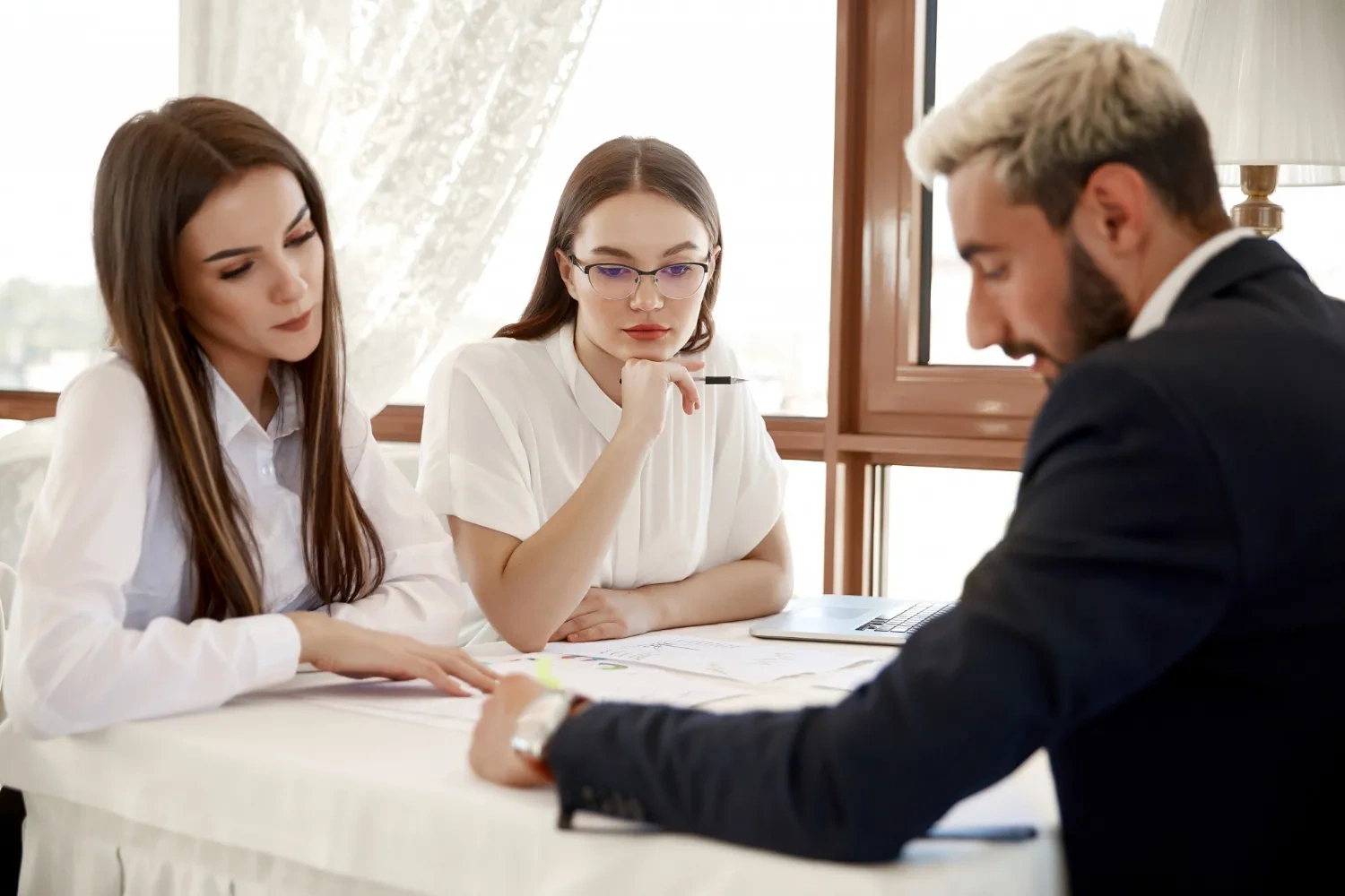 Team meeting: Two women and a man review documents at a table, possibly discussing ASIC IDR data for charities.