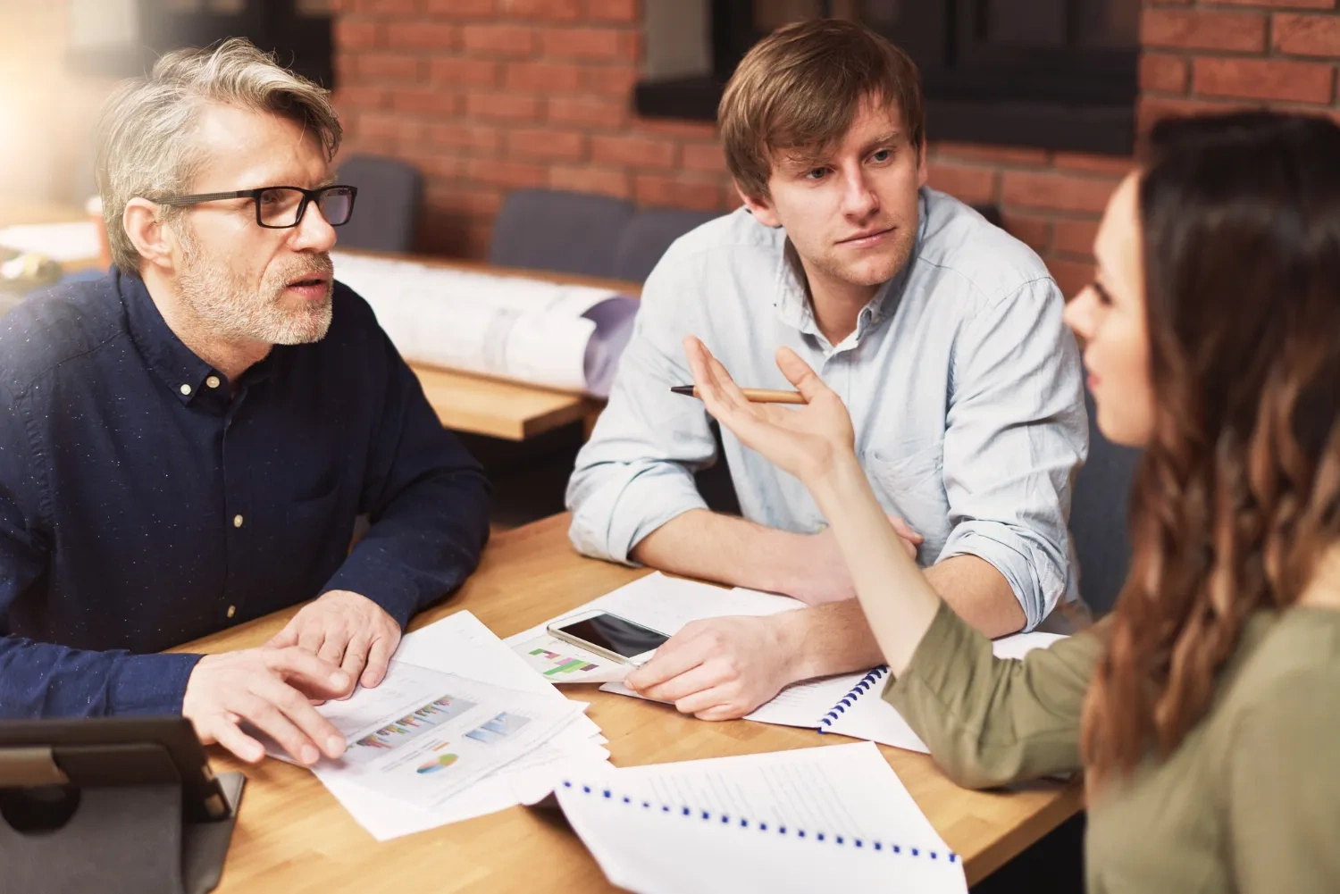 Team discussing documents at a table, possibly related to member information requests.