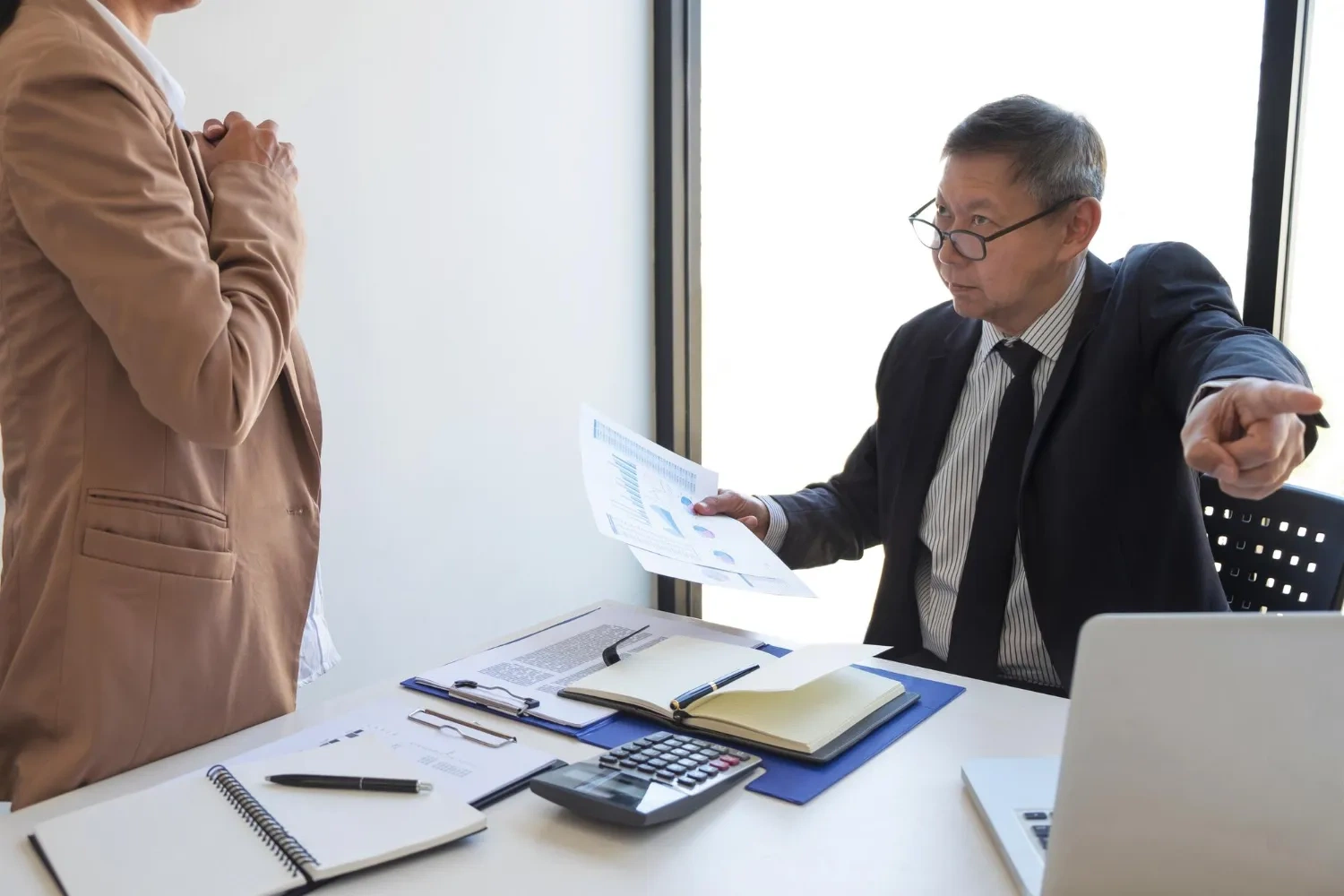 Angry boss pointing at employee with financial charts. Workplace conflict.