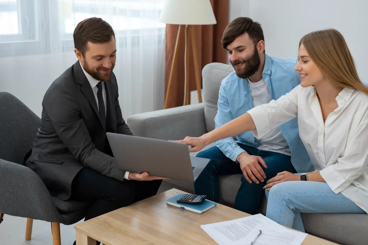 Financial advisor showing laptop to a couple during asset recovery consultation.