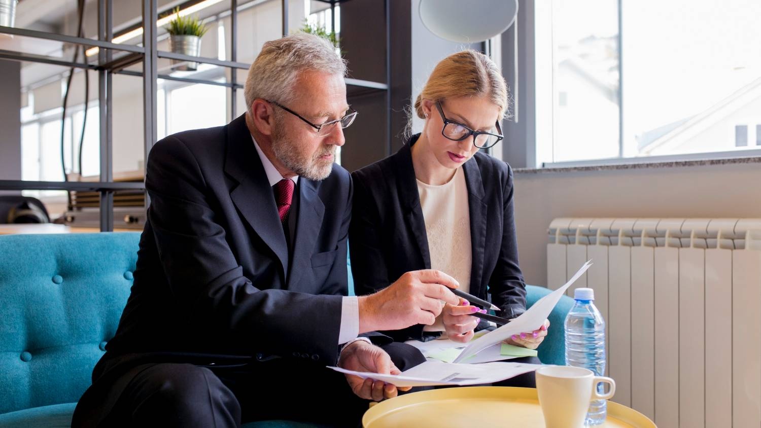 Two business professionals reviewing documents in an office setting.