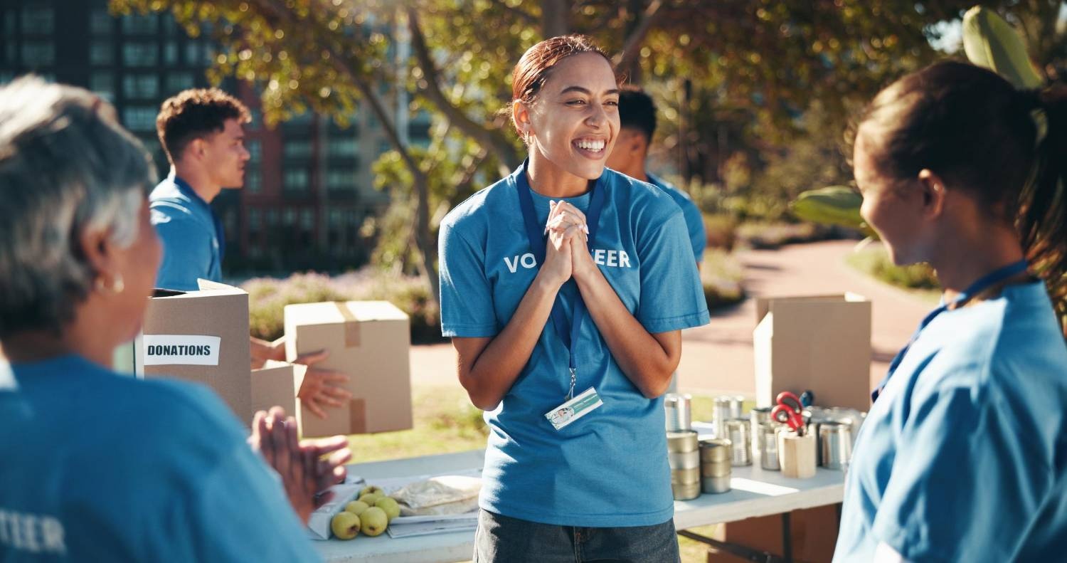 Volunteers at charity event collecting donations, including canned goods and boxes.