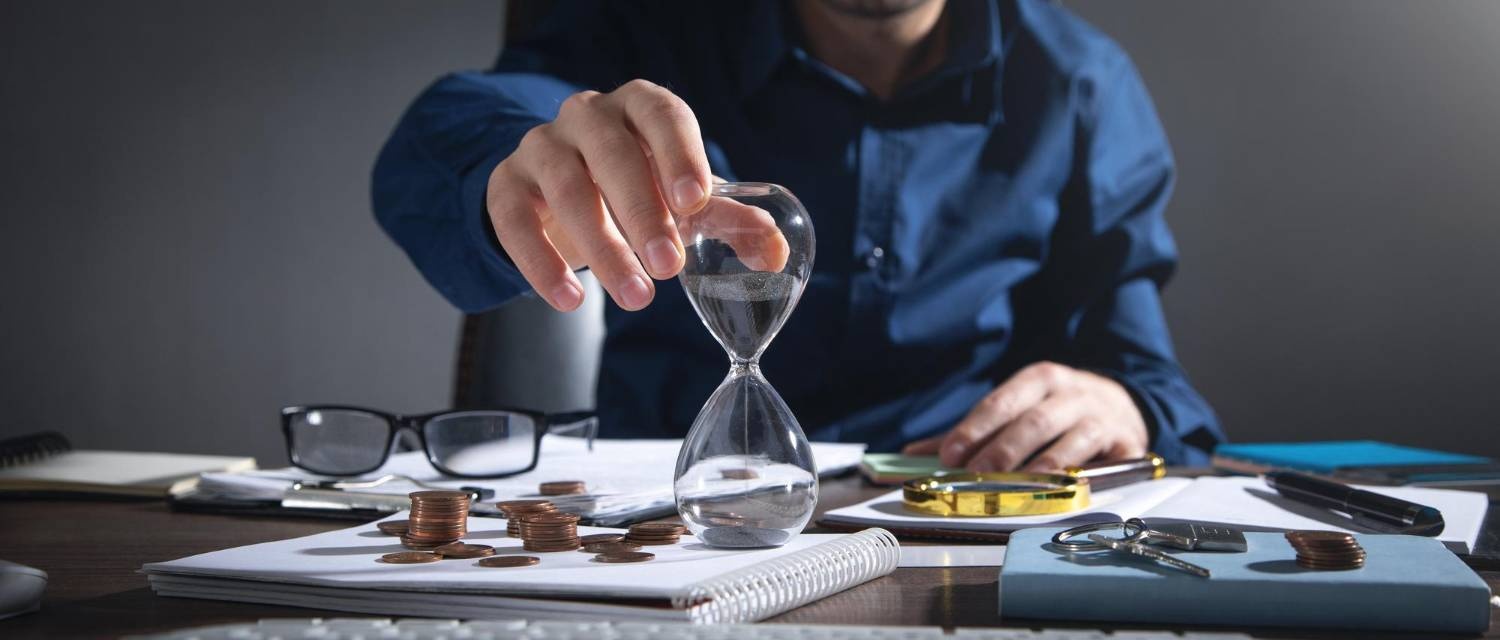 Hourglass, coins, and paperwork on a desk, symbolizing time management for ACNC compliance in Australian charities.