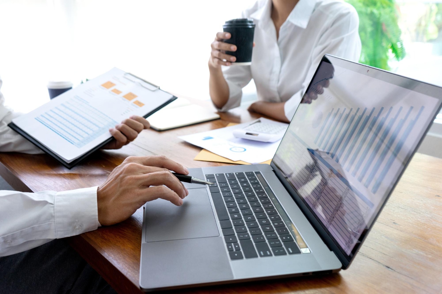 Team analyzing financial reports and data on a laptop during a meeting.