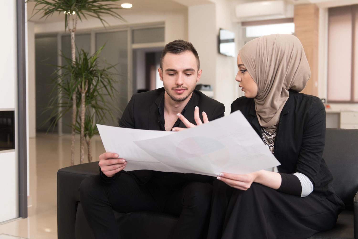 Business colleagues, one wearing a hijab, reviewing documents. Estate dispute resolution concept.