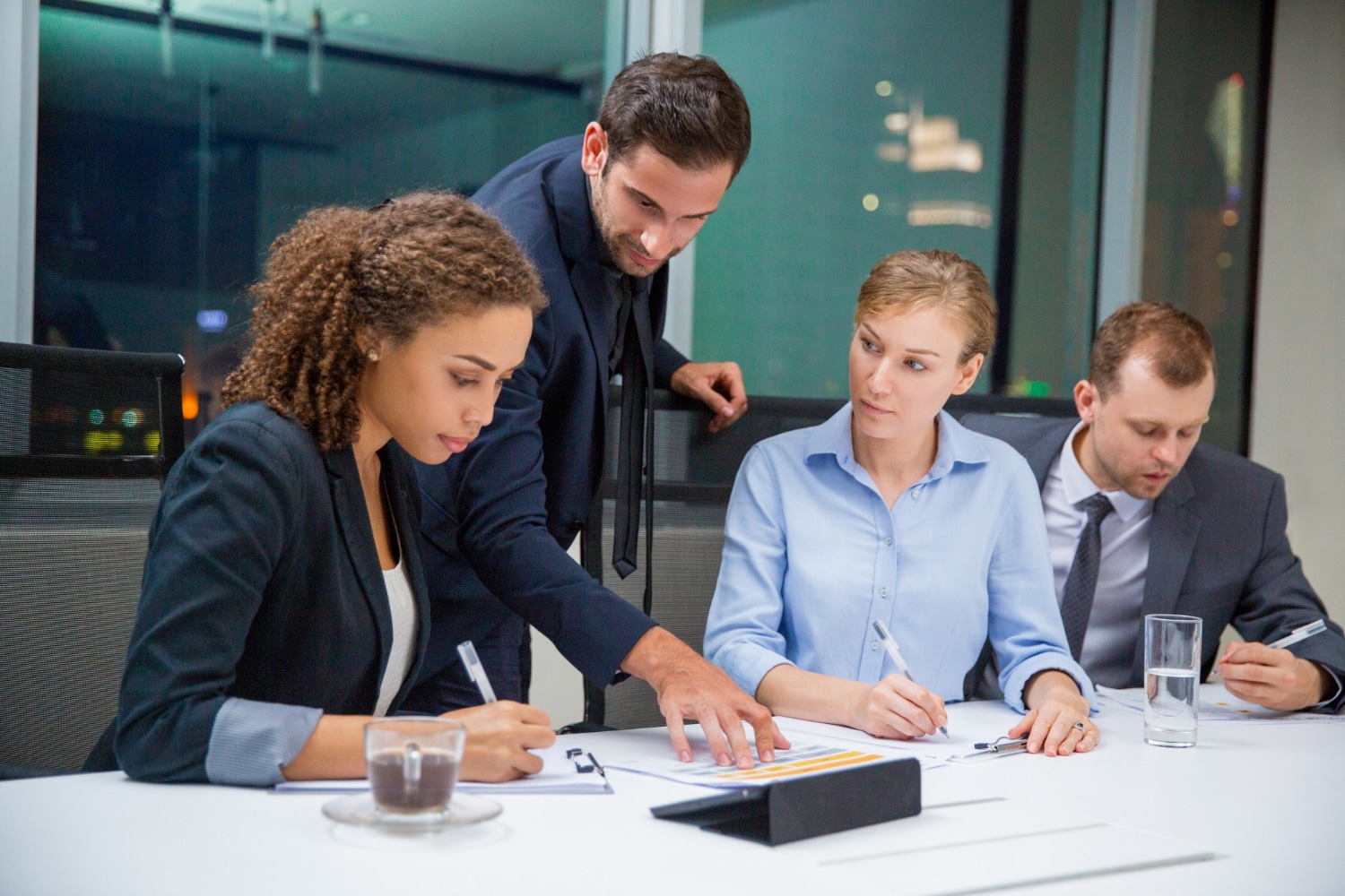 Business meeting: Four professionals review documents at a table.