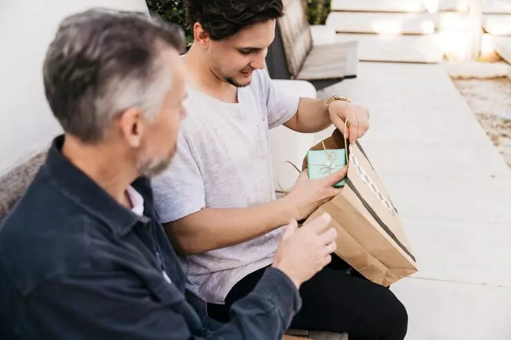 Son giving father a gift; a thoughtful moment.