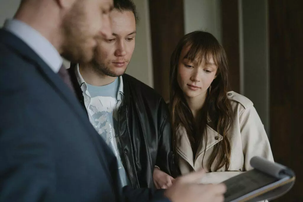 Business meeting: a real estate agent discusses paperwork with a couple, likely regarding ACNC or ASIC compliance.