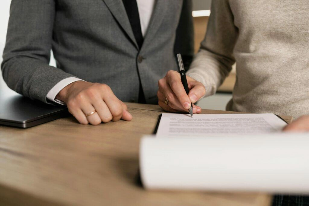 Close-up of hands signing NSW building contract.
