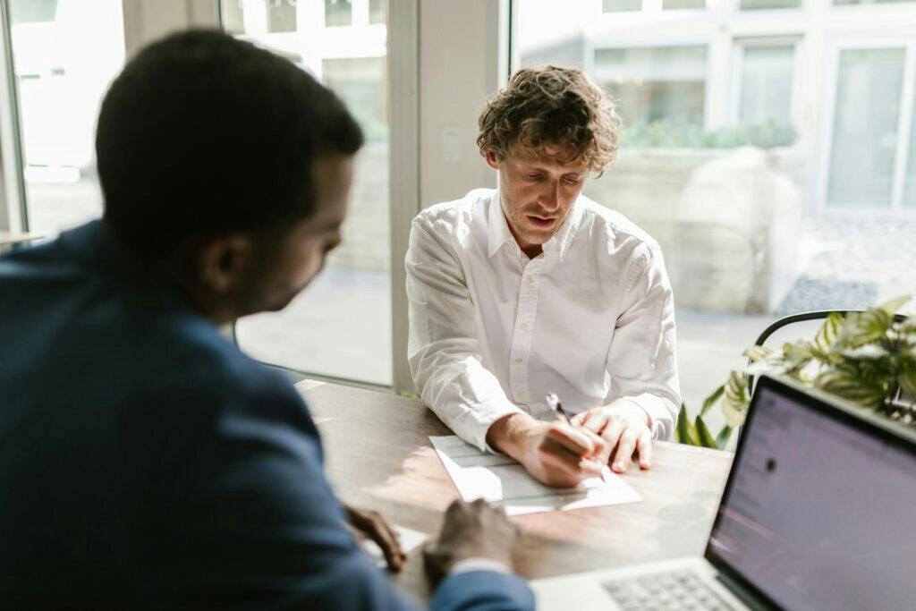 Two businesspeople review NSW building contract paperwork at a table.