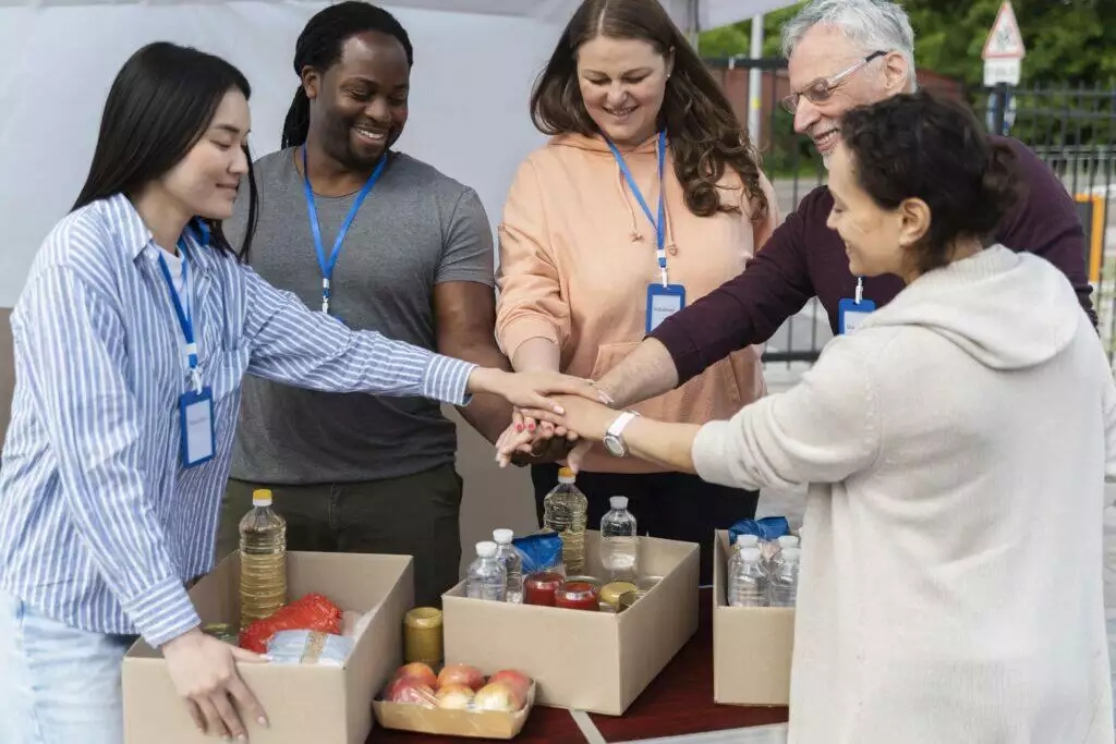 Diverse group of volunteers stacking hands, showing teamwork and support for charity work.