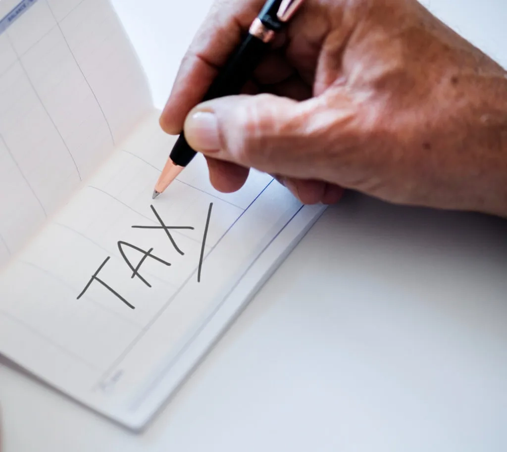 Hand writing 'TAX' on a checkbook, planning tax concessions for nonprofits.