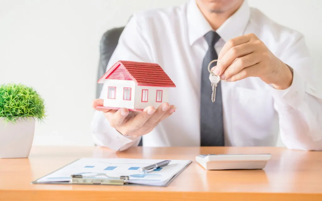 Real estate agent handing over house keys and model home