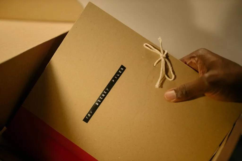 Hand holding a tied manila folder labeled