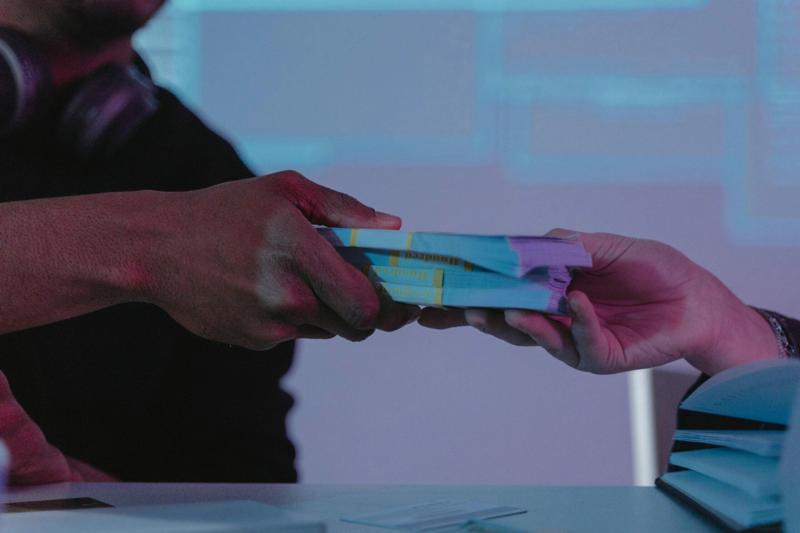 Hands exchanging a stack of cash, symbolizing financial transactions for non-profit organizations needing legal assistance.