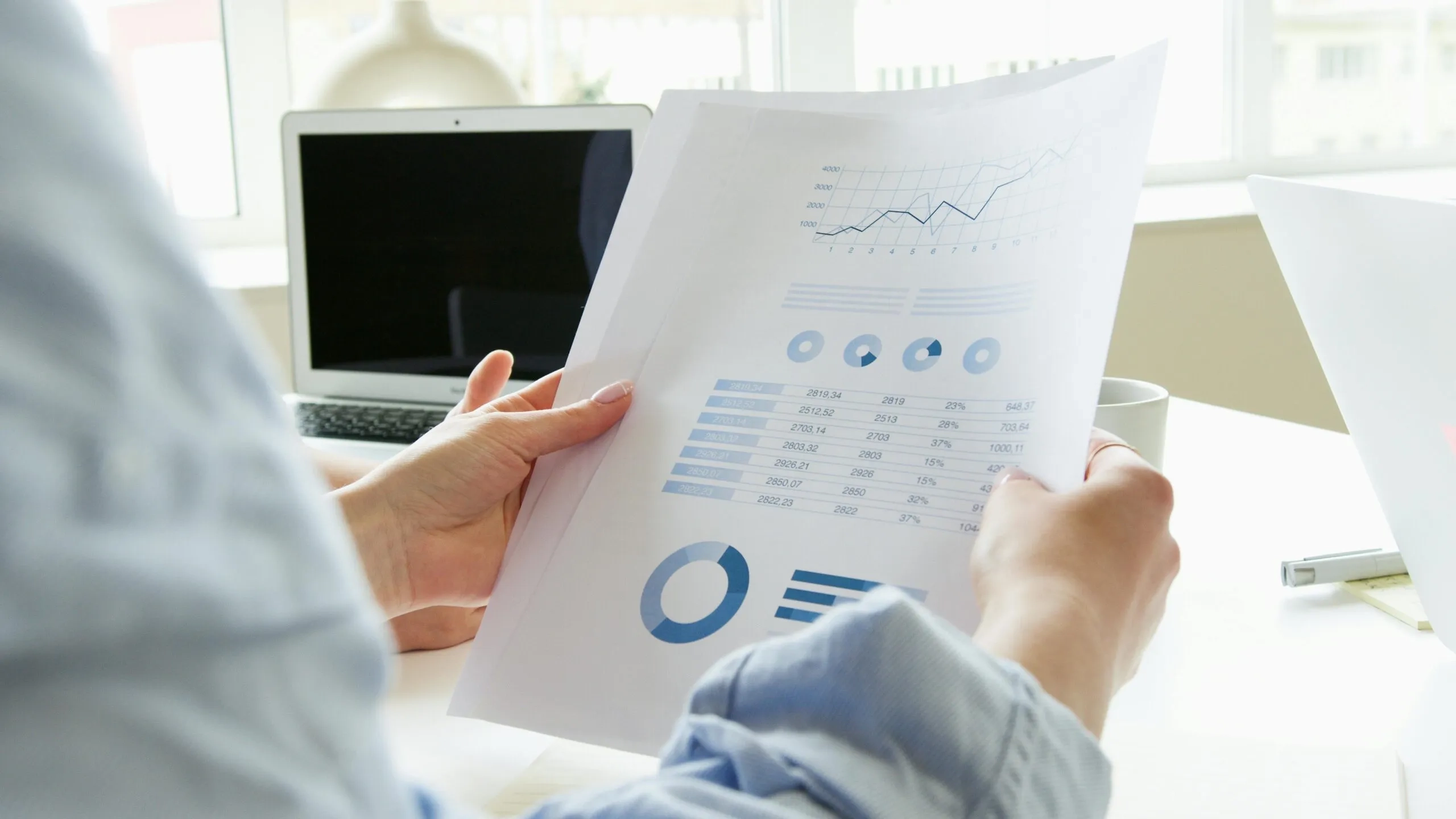 Person analyzing financial charts and data on a document.