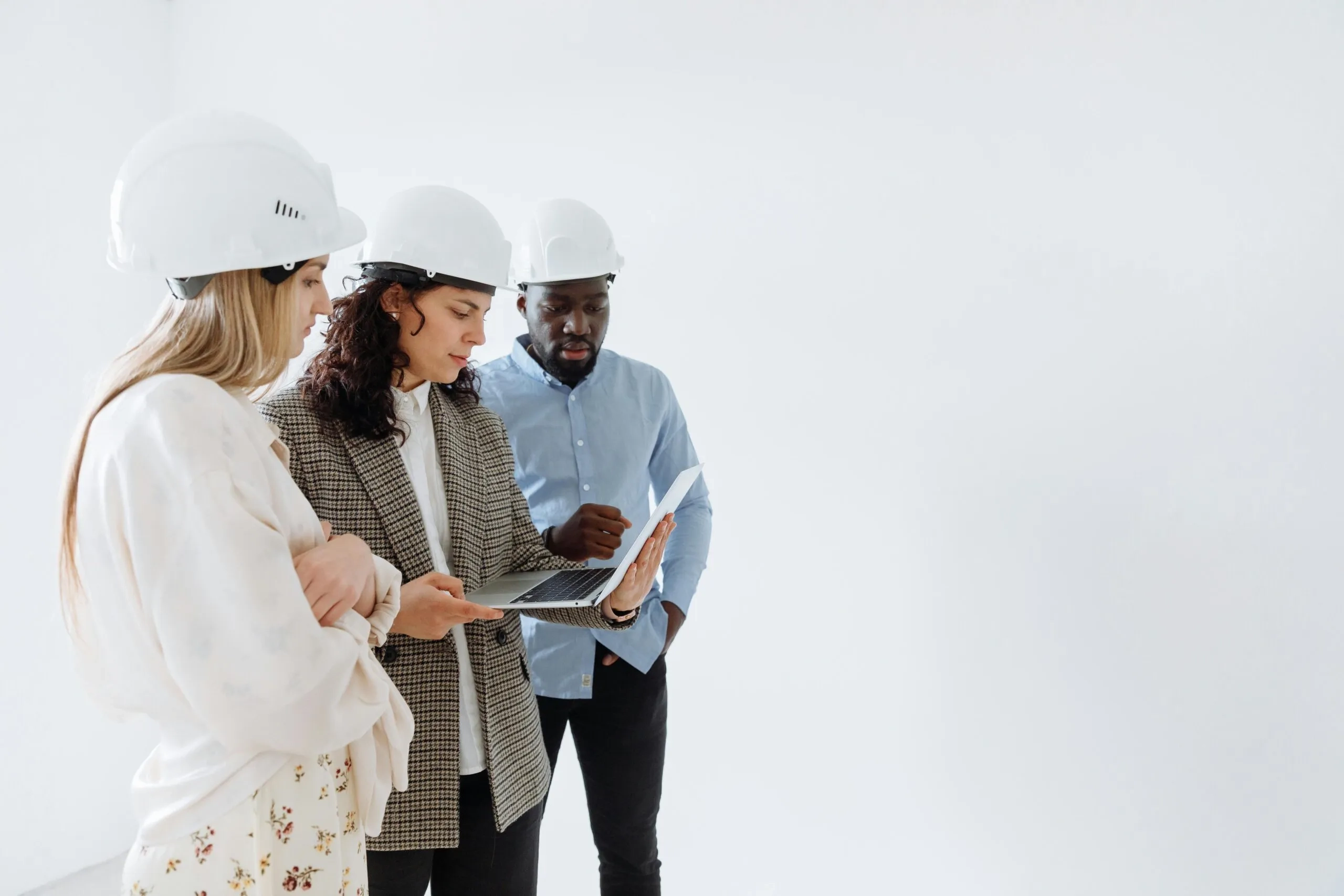 Property developers reviewing contracts on laptop. NSW construction team in hard hats.